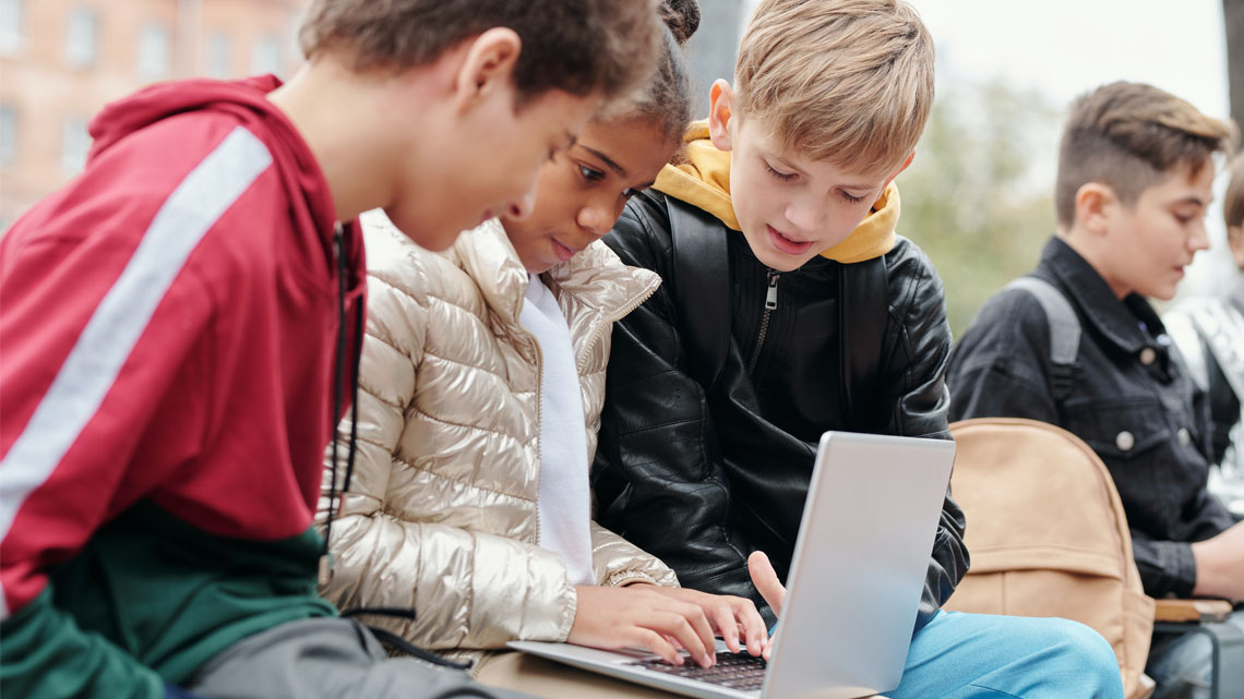 Symbolbild: 3 Jugendliche, die sich gemeinsam etwas auf einem Laptop ansehen